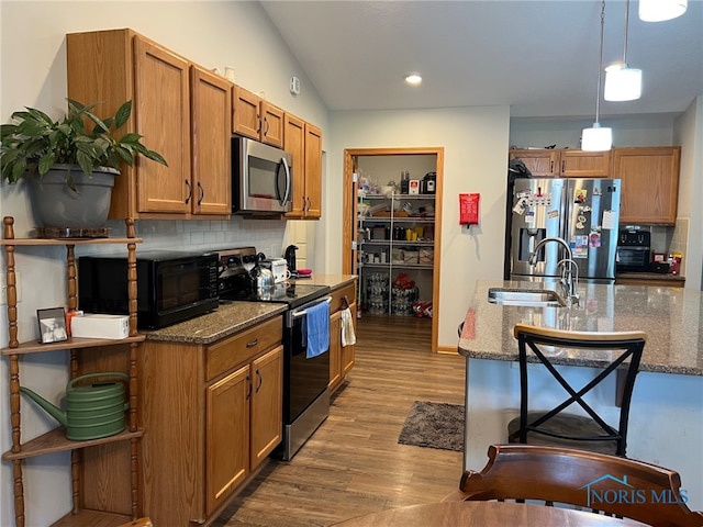 606 Polaris Dr, Upper Sandusky, OH 43351 - kitchen featuring appliances with stainless steel finishes, a sink, wood finished floors, brown cabinets, and lofted ceiling