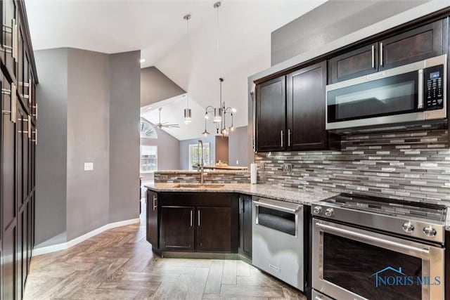 9845 Connor Lake Cir, Perrysburg, OH 43551 - kitchen featuring appliances with stainless steel finishes, dark brown cabinets, lofted ceiling, a peninsula, and light stone countertops