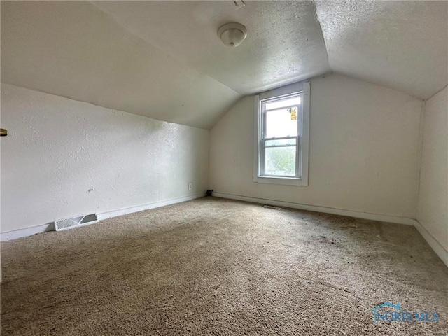 678 Lorain St, Toledo, OH 43609 - additional living space with vaulted ceiling, baseboards, carpet floors, and a textured ceiling