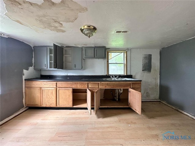 678 Lorain St, Toledo, OH 43609 - kitchen with open shelves, light wood-type flooring, baseboards, dark countertops, and a sink
