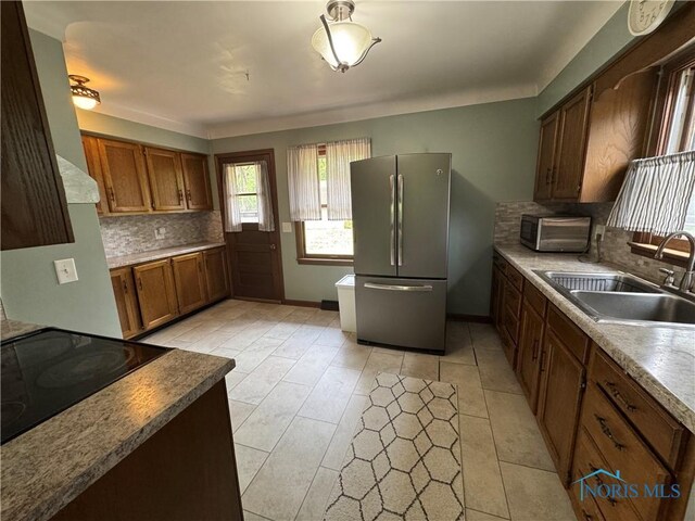 4538 Vineyard Rd, Toledo, OH 43623 - kitchen with freestanding refrigerator, a sink, decorative backsplash, cooktop, and brown cabinets