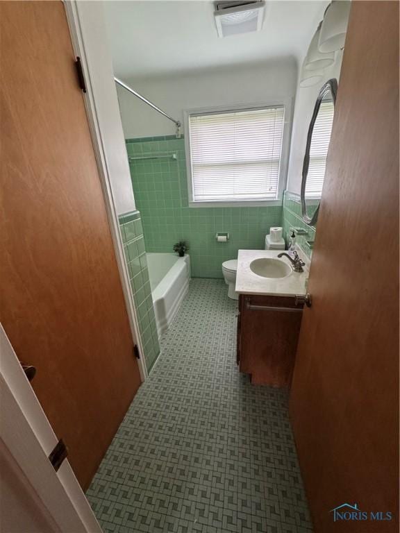 4538 Vineyard Rd, Toledo, OH 43623 - full bath featuring vanity, toilet, washtub / shower combination, tile patterned floors, and tile walls