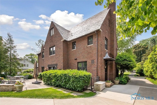 3534 Edgevale Rd, Ottawa Hills, OH 43606 - view of home's exterior with a high end roof, brick siding, a patio, and a chimney