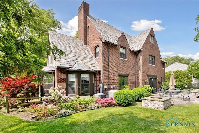 3534 Edgevale Rd, Ottawa Hills, OH 43606 - rear view of house featuring a high end roof, a patio area, brick siding, a lawn, and a chimney