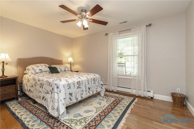 7915 W Bancroft St, Toledo, OH 43617 - bedroom featuring baseboard heating, wood finished floors, baseboards, and ceiling fan