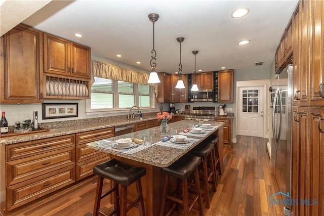 7915 W Bancroft St, Toledo, OH 43617 - kitchen with appliances with stainless steel finishes, brown cabinetry, a breakfast bar area, dark wood finished floors, and recessed lighting