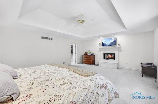 8832 Orchard Lake Rd, Holland, OH 43528 - carpeted bedroom featuring a raised ceiling, a glass covered fireplace, baseboards, and a ceiling fan