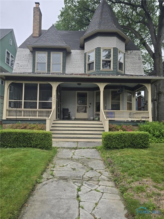 2267 Robinwood Ave, Toledo, OH 43620 - victorian house featuring a chimney, a porch, and a front lawn