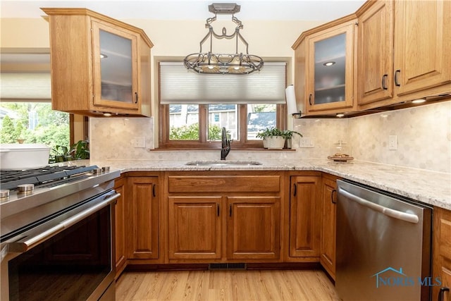 2439 Notting Hill Rd, Toledo, OH 43617 - kitchen featuring stainless steel appliances, a sink, light stone countertops, light wood-style floors, and decorative backsplash
