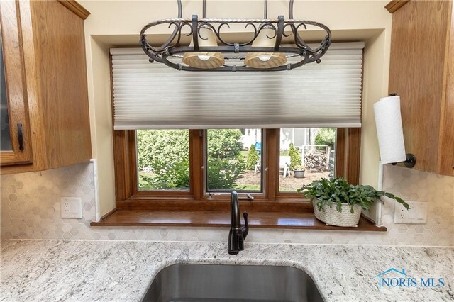 2439 Notting Hill Rd, Toledo, OH 43617 - kitchen view of a sink, backsplash, brown cabinets, and light stone countertops