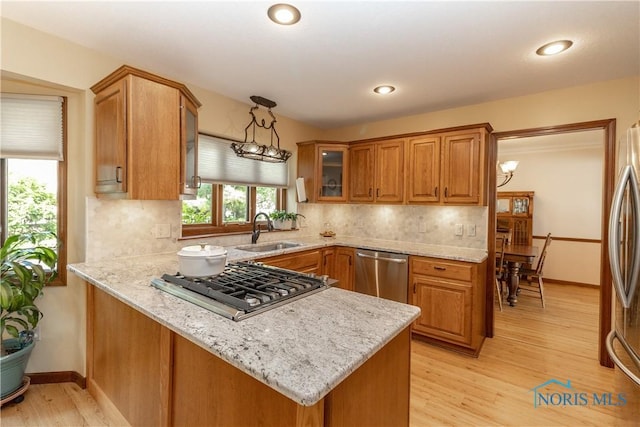 2439 Notting Hill Rd, Toledo, OH 43617 - kitchen with stainless steel appliances, a peninsula, a sink, brown cabinets, and light stone countertops