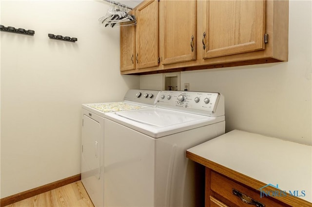 2439 Notting Hill Rd, Toledo, OH 43617 - laundry room featuring cabinet space, washer and clothes dryer, light wood-style flooring, and baseboards