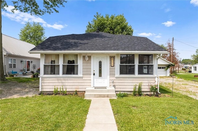 254 N Worthy St, Marblehead, OH 43440 - bungalow featuring a front yard, roof with shingles, and a garage