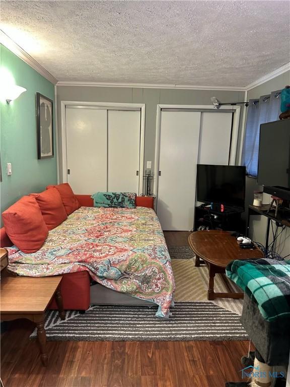 314 Jewett Ave, North Baltimore, OH 45872 - bedroom with wood finished floors, multiple closets, ornamental molding, and a textured ceiling