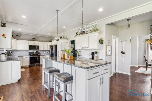 1209 Apache Dr, Wauseon, OH 43567 - kitchen with stainless steel appliances, dark stone countertops, white cabinetry, a kitchen breakfast bar, and recessed lighting
