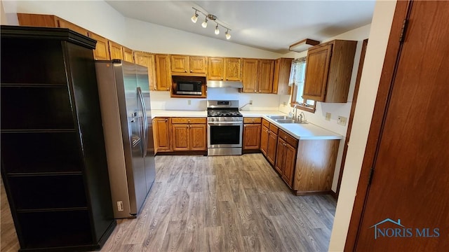 2384 State Route 109, Delta, OH 43515 - kitchen featuring stainless steel appliances, vaulted ceiling, light wood finished floors, brown cabinetry, and under cabinet range hood