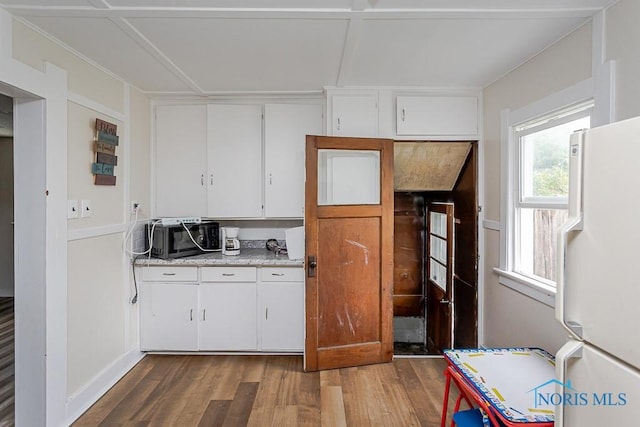 635 Plymouth St, Toledo, OH 43605 - kitchen with freestanding refrigerator, wood finished floors, light countertops, and white cabinets