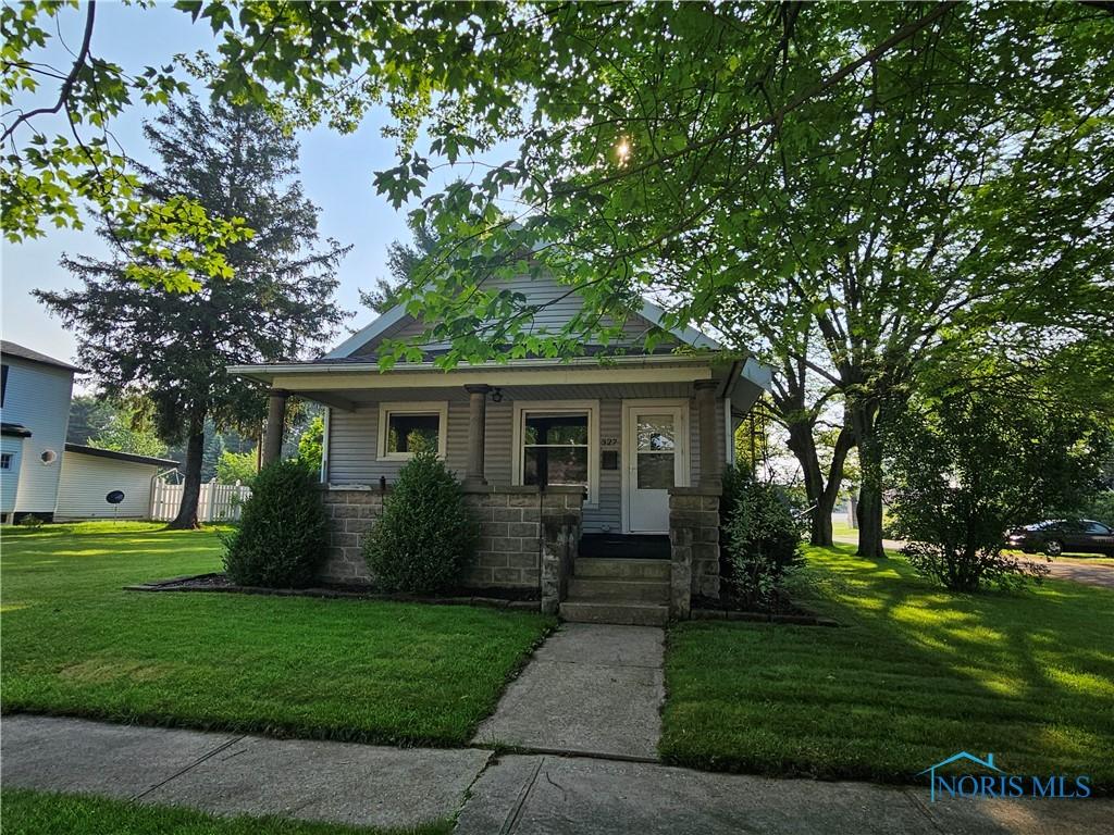 327 Osceola Ave, Defiance, OH 43512 - view of front of home featuring a front lawn, covered porch, and stone siding