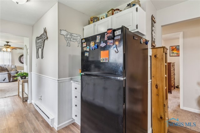 8399 W State Route 12, Fostoria, OH 44830 - kitchen with freestanding refrigerator, a baseboard radiator, white cabinetry, a ceiling fan, and a wainscoted wall