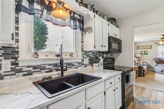 8399 W State Route 12, Fostoria, OH 44830 - kitchen featuring black appliances, a sink, white cabinets, decorative backsplash, and wood finished floors