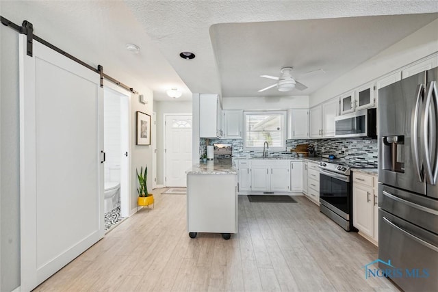 2543 Broadway St Unit 2543, Toledo, OH 43609 - kitchen featuring appliances with stainless steel finishes, a barn door, a sink, a ceiling fan, and backsplash