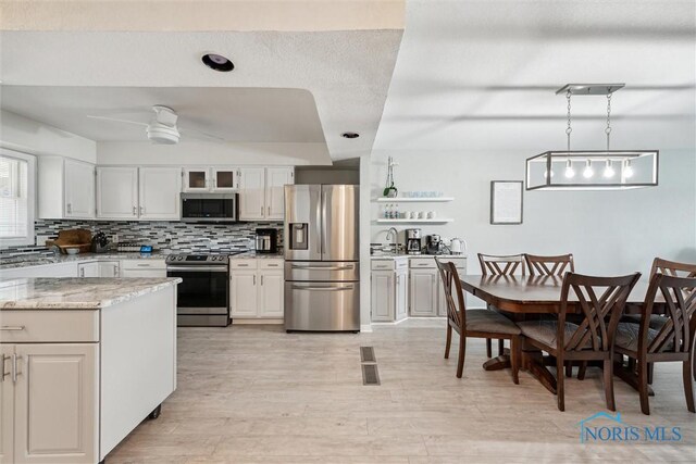 2543 Broadway St Unit 2543, Toledo, OH 43609 - kitchen featuring stainless steel appliances, tasteful backsplash, a ceiling fan, light wood-style flooring, and light stone countertops