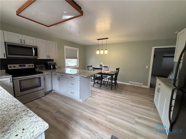 803 W Holland St, Archbold, OH 43502 - kitchen featuring stainless steel appliances, a peninsula, white cabinets, and light stone countertops