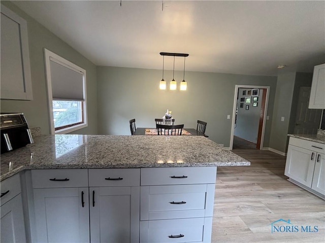 803 W Holland St, Archbold, OH 43502 - kitchen featuring a peninsula, white cabinets, light wood-type flooring, light stone counters, and decorative light fixtures