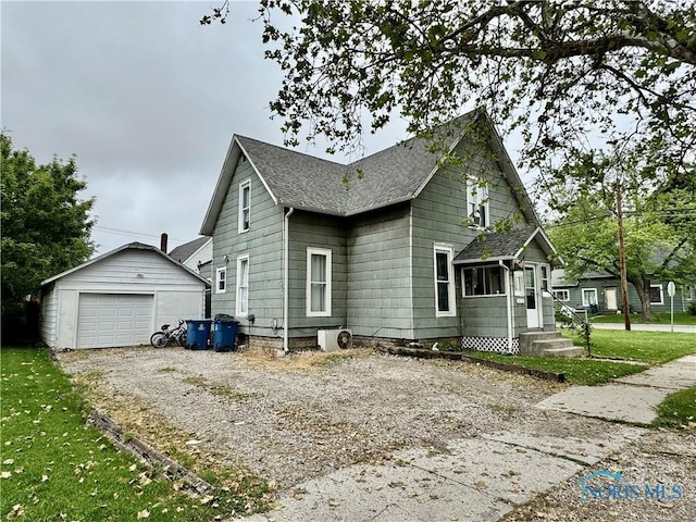 335 N Cherry St, Bryan, OH 43506 - view of property exterior with a detached garage, an outbuilding, a shingled roof, and driveway