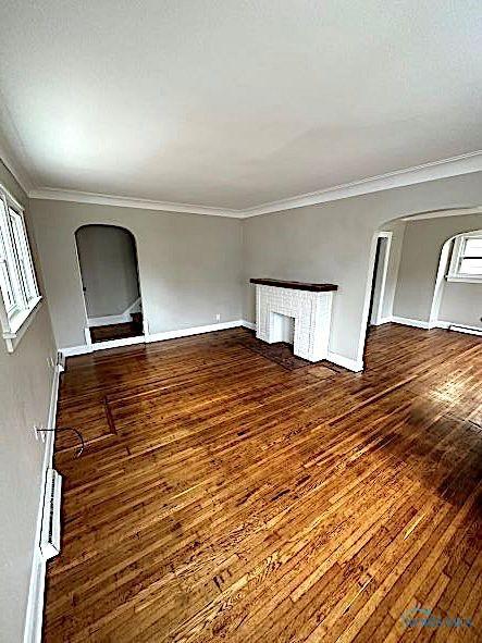 1739 Wyndhurst Rd, Toledo, OH 43607 - empty room with arched walkways, hardwood / wood-style floors, ornamental molding, and baseboards