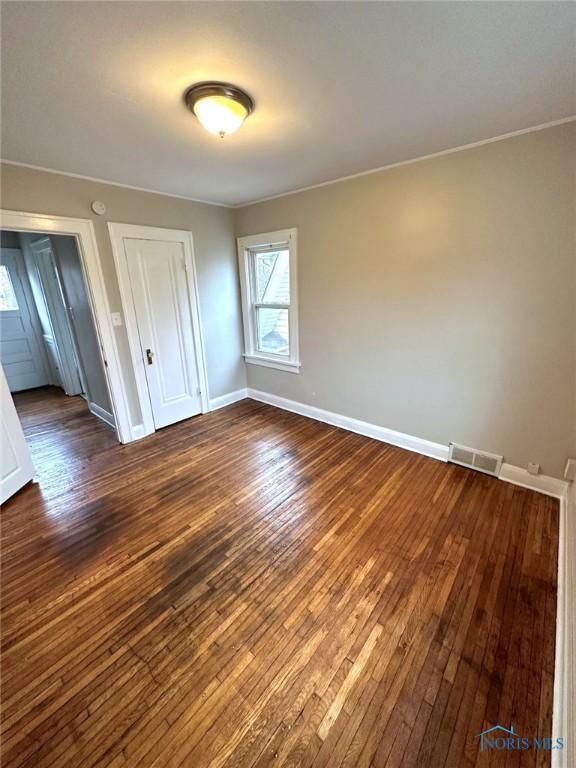 1739 Wyndhurst Rd, Toledo, OH 43607 - unfurnished bedroom featuring dark wood-style flooring, baseboards, a closet, and ornamental molding