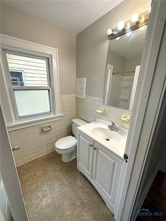 1739 Wyndhurst Rd, Toledo, OH 43607 - full bath featuring tile walls, toilet, vanity, a textured ceiling, and a wainscoted wall