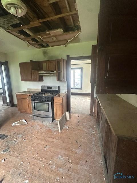 831 Oak St, Toledo, OH 43605 - kitchen with gas stove, brown cabinetry, and under cabinet range hood