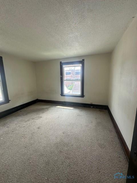 831 Oak St, Toledo, OH 43605 - empty room featuring carpet, baseboards, and a textured ceiling