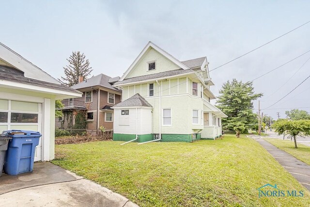 2740 Robinwood Ave, Toledo, OH 43610 - view of side of home featuring a lawn, stucco siding, and a shingled roof