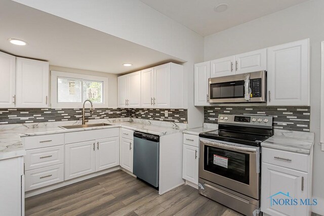 2740 Robinwood Ave, Toledo, OH 43610 - kitchen featuring appliances with stainless steel finishes, decorative backsplash, white cabinets, wood finished floors, and recessed lighting