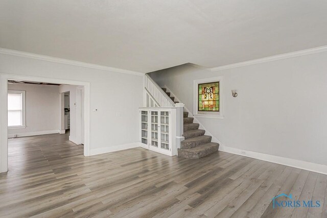 2740 Robinwood Ave, Toledo, OH 43610 - unfurnished living room featuring crown molding, wood finished floors, and stairway