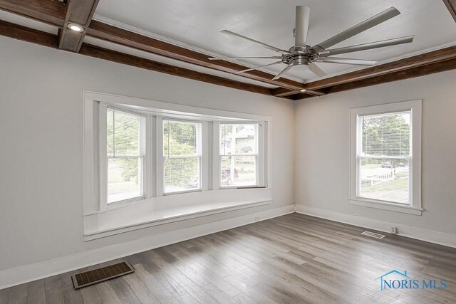 2740 Robinwood Ave, Toledo, OH 43610 - empty room with healthy amount of natural light, beam ceiling, a ceiling fan, and wood finished floors