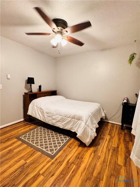 1019 E Wilson St, Bryan, OH 43506 - bedroom with a textured ceiling, wood finished floors, ceiling fan, and baseboards