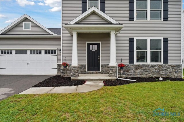 8805 Birchfield Rd, Sylvania, OH 43560 - view of front of property featuring stone siding, a front lawn, a garage, and asphalt driveway