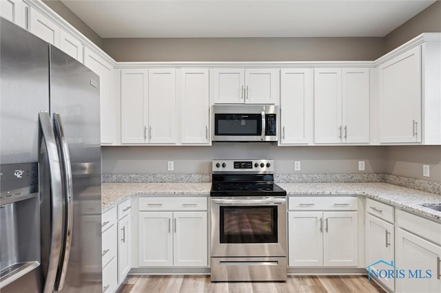 8805 Birchfield Rd, Sylvania, OH 43560 - kitchen with stainless steel appliances, white cabinetry, light wood finished floors, and light stone counters