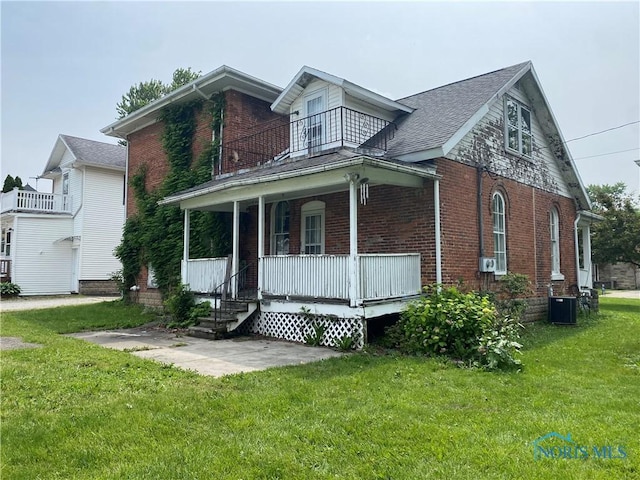 232 N Franklin St, Wauseon, OH 43567 - view of front facade with a balcony, brick siding, cooling unit, and covered porch