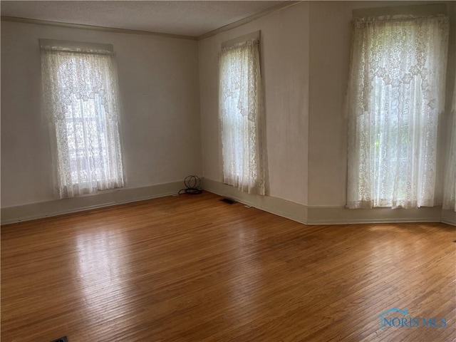232 N Franklin St, Wauseon, OH 43567 - spare room featuring wood finished floors, crown molding, baseboards, and a textured ceiling
