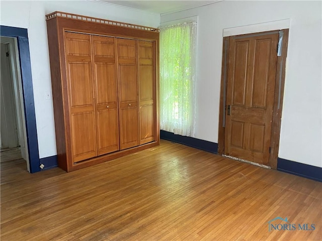 232 N Franklin St, Wauseon, OH 43567 - unfurnished bedroom with light wood finished floors, baseboards, crown molding, and a closet