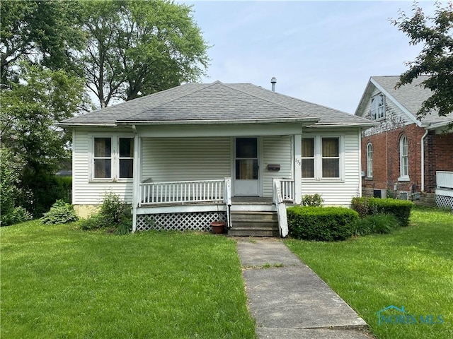 238 N Franklin St, Wauseon, OH 43567 - bungalow-style house featuring roof with shingles, a front yard, and covered porch
