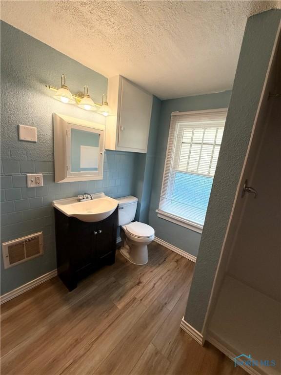 5455 Douglas Rd, Toledo, OH 43613 - bathroom featuring a textured ceiling, wood finished floors, vanity, and a shower