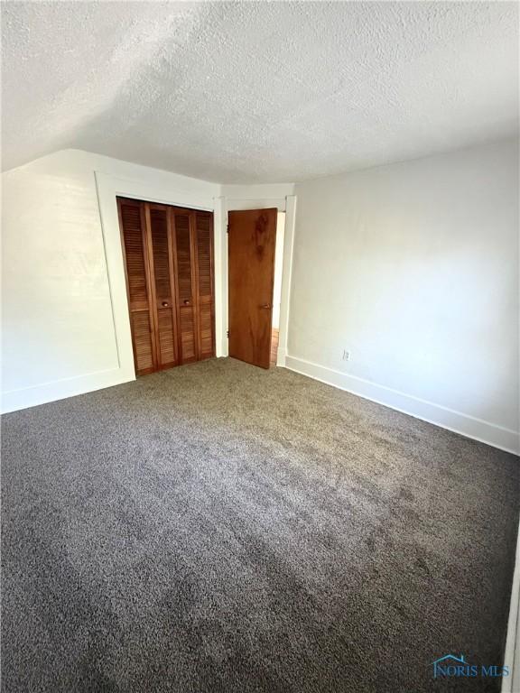 5455 Douglas Rd, Toledo, OH 43613 - unfurnished bedroom with a textured ceiling, carpet, a closet, and vaulted ceiling