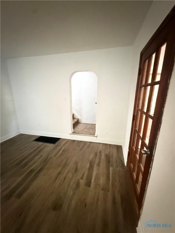 5455 Douglas Rd, Toledo, OH 43613 - unfurnished room with dark wood finished floors, arched walkways, and stairway