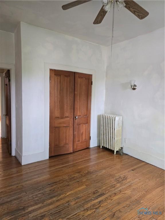 336 Holgate Ave, Defiance, OH 43512 - unfurnished bedroom with radiator heating unit, wood finished floors, a ceiling fan, and a closet