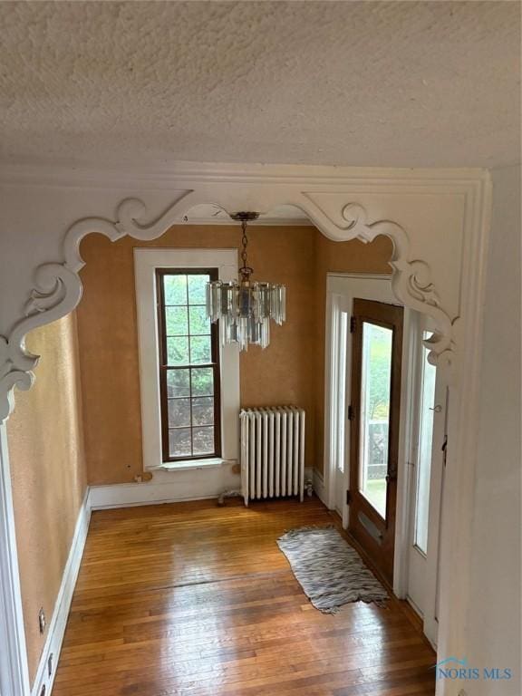 336 Holgate Ave, Defiance, OH 43512 - unfurnished dining area featuring radiator, a textured ceiling, a chandelier, and wood finished floors